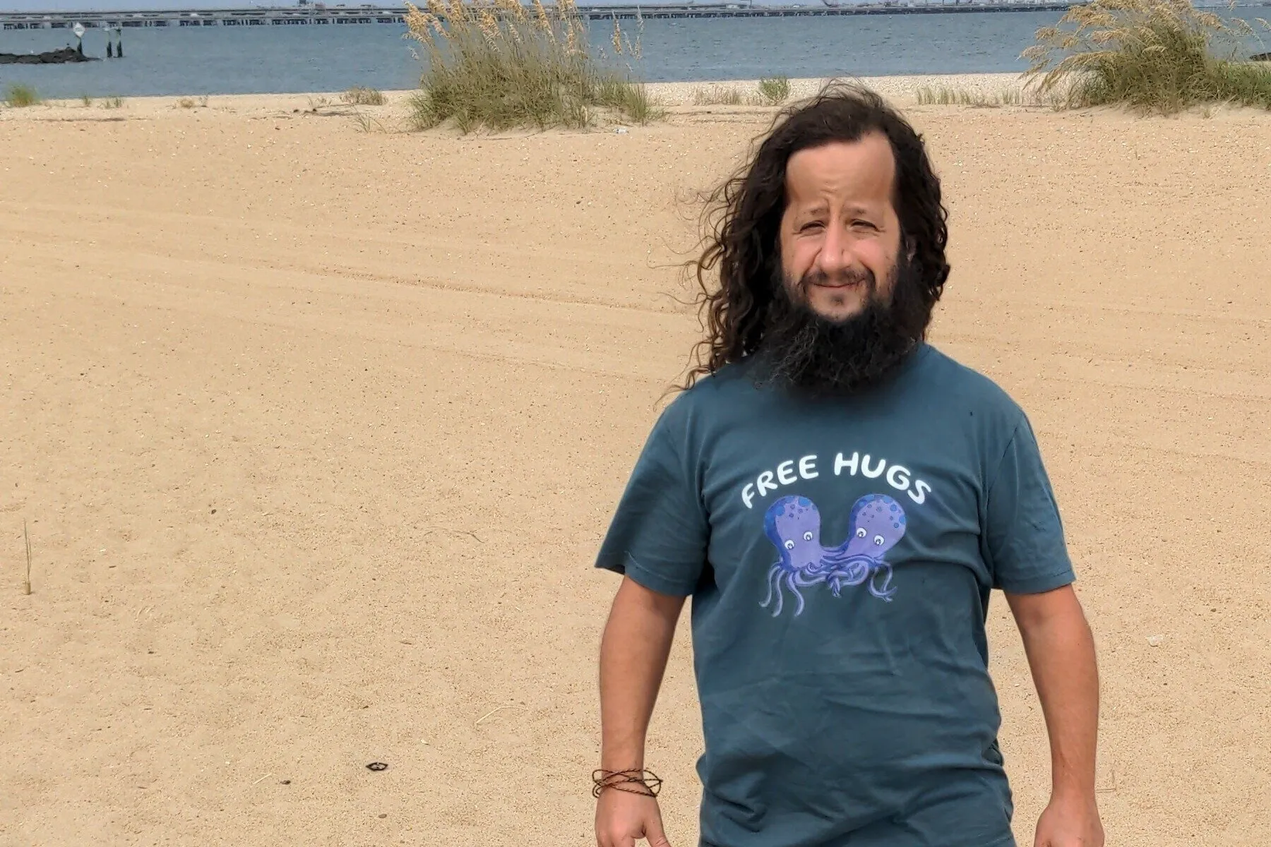 David Barbarisi standing on a beach wearing a grey 'Free Hugs' t-shirt with an octopus graphic